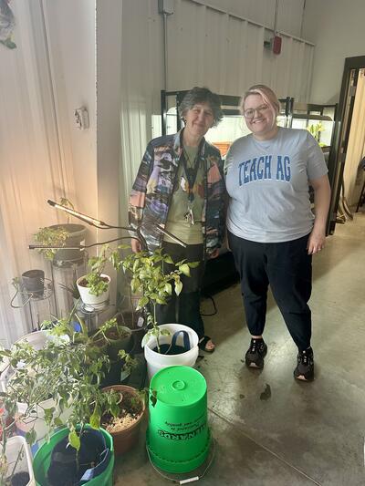 2 female teachers pose with plants